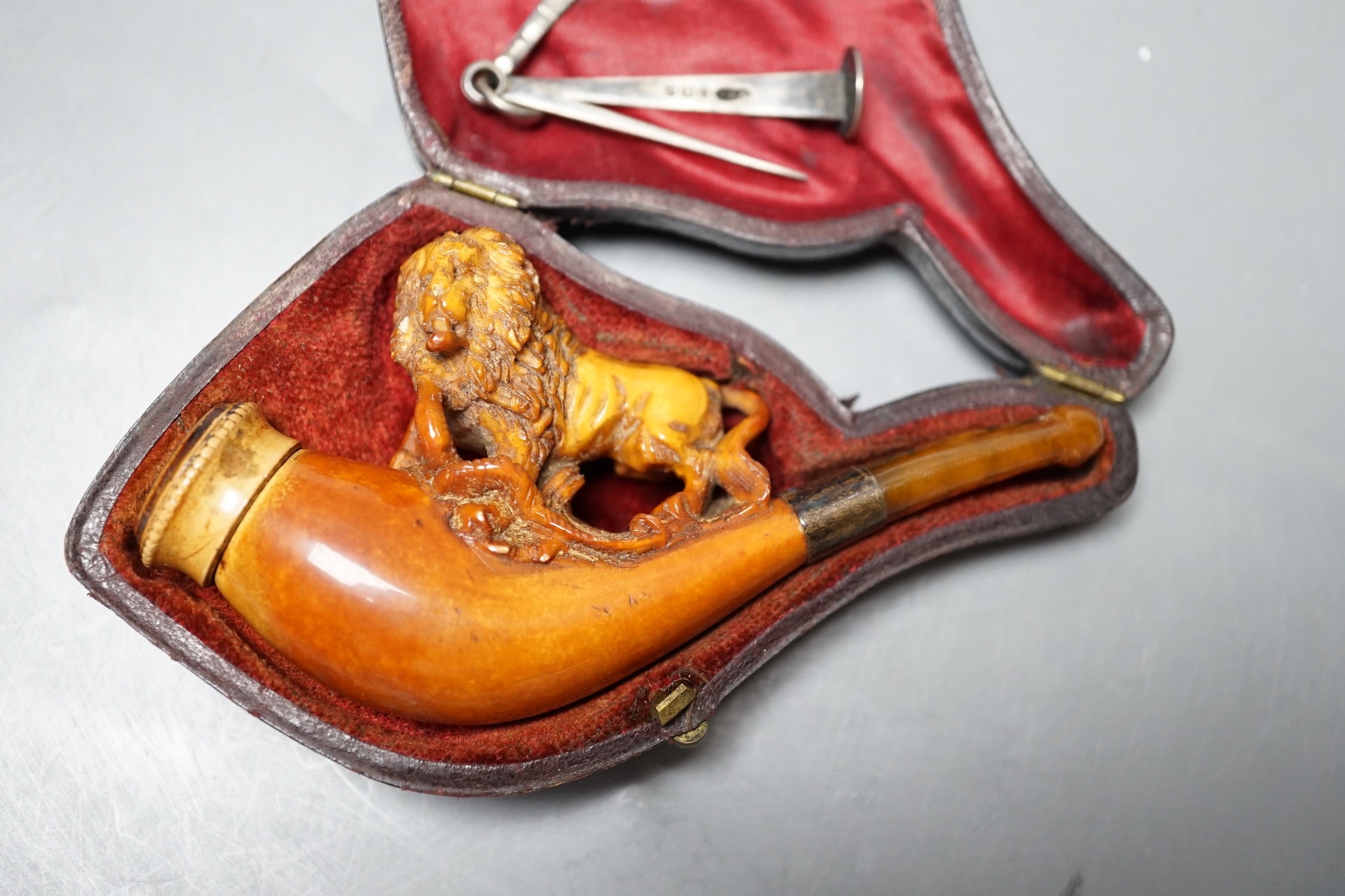 A cased Meerschaum cheroot holder with a carved wooden lion decoration with silver cleaner in fitted case, 12cm overall